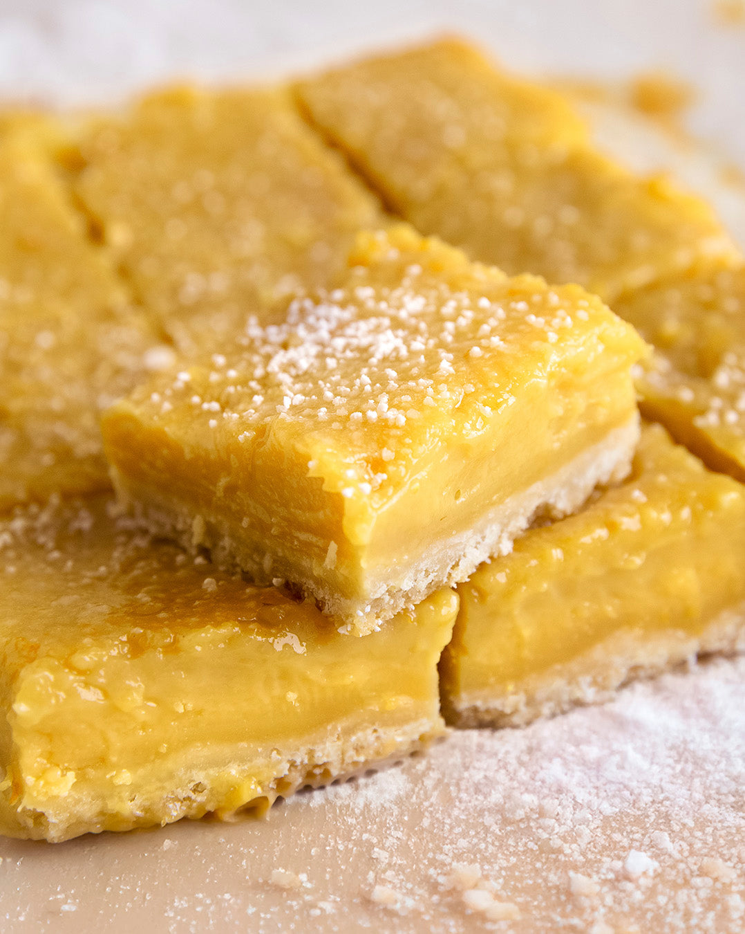Close-up of lemon bars with a powdered sugar topping on a light background